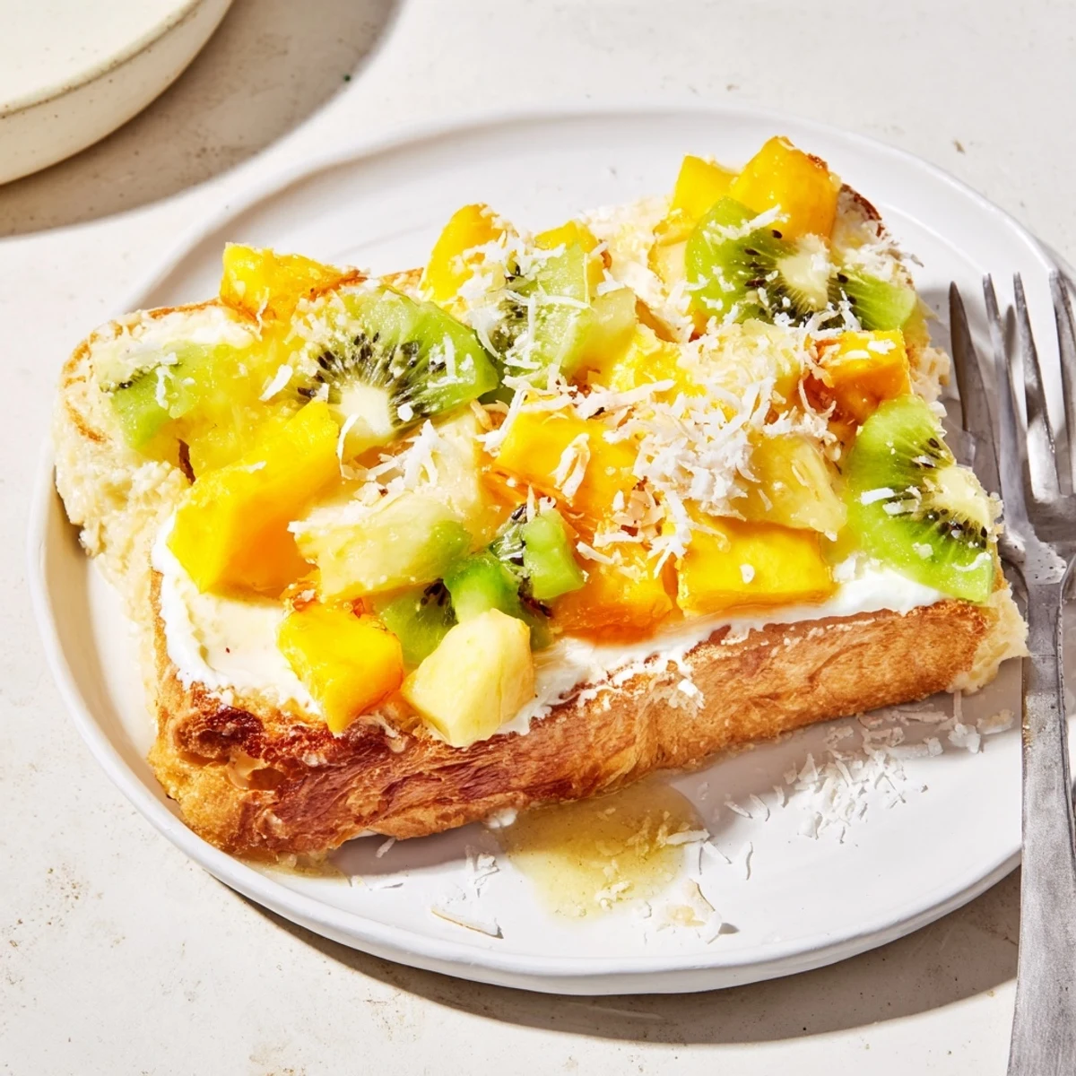 Yogurt-Custard Toast 2.0 topped with vibrant mango, kiwi, and coconut sprinkles.  
