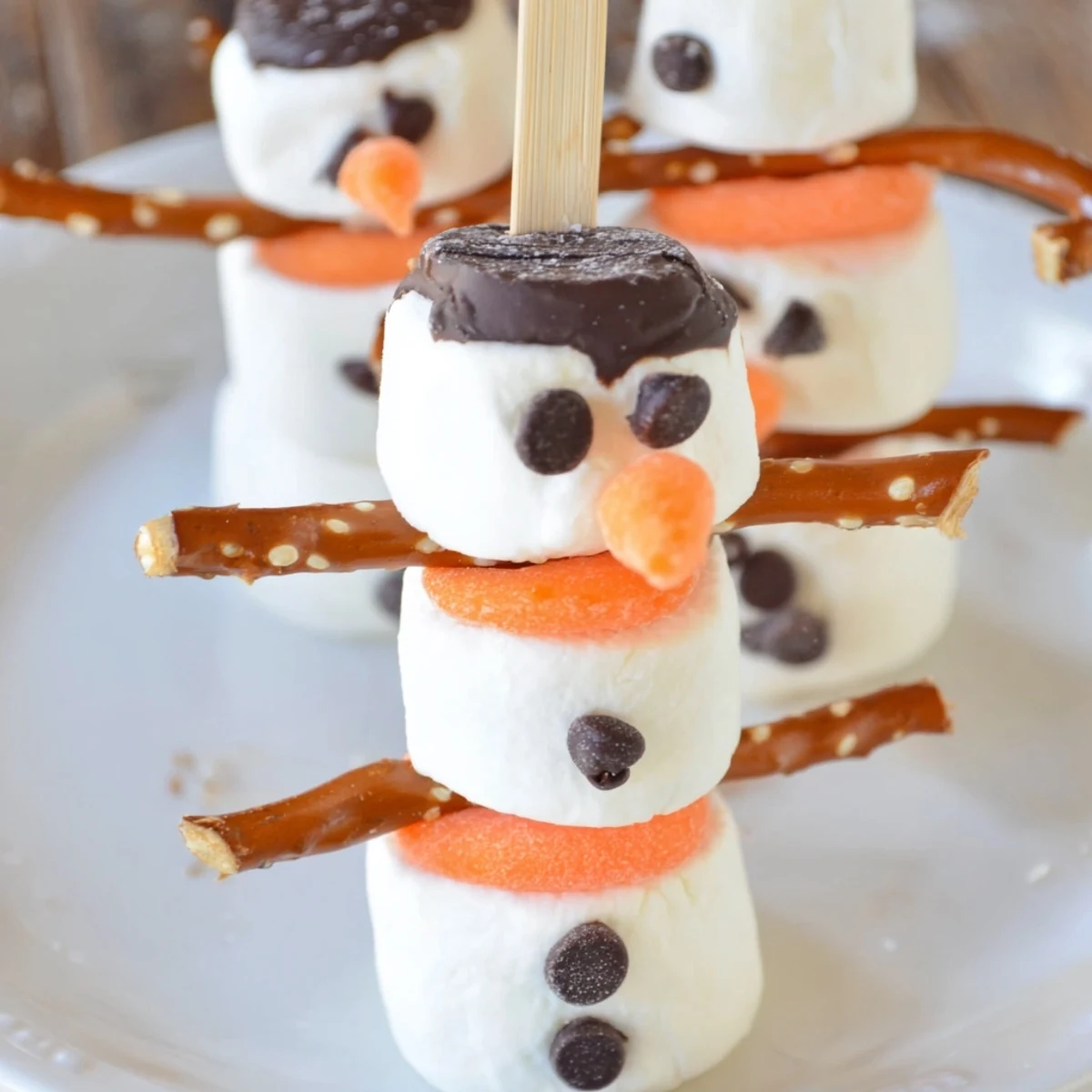 Festive marshmallow snowman stick arrangement, ready for a winter treat; decorated snowmen on sticks.