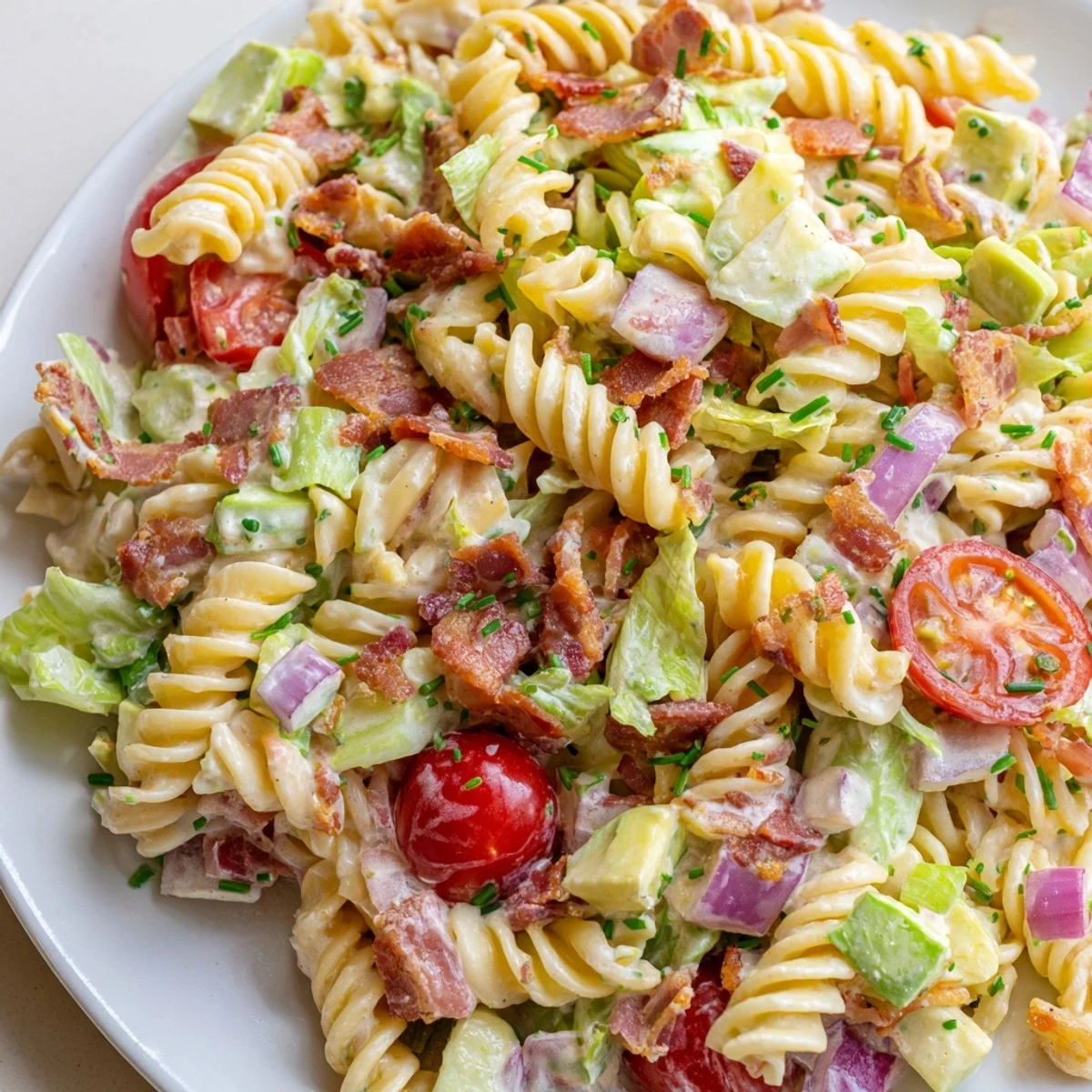 BLT Pasta Salad, a colorful mix of pasta, bacon, and tomatoes, awaits on a plate.