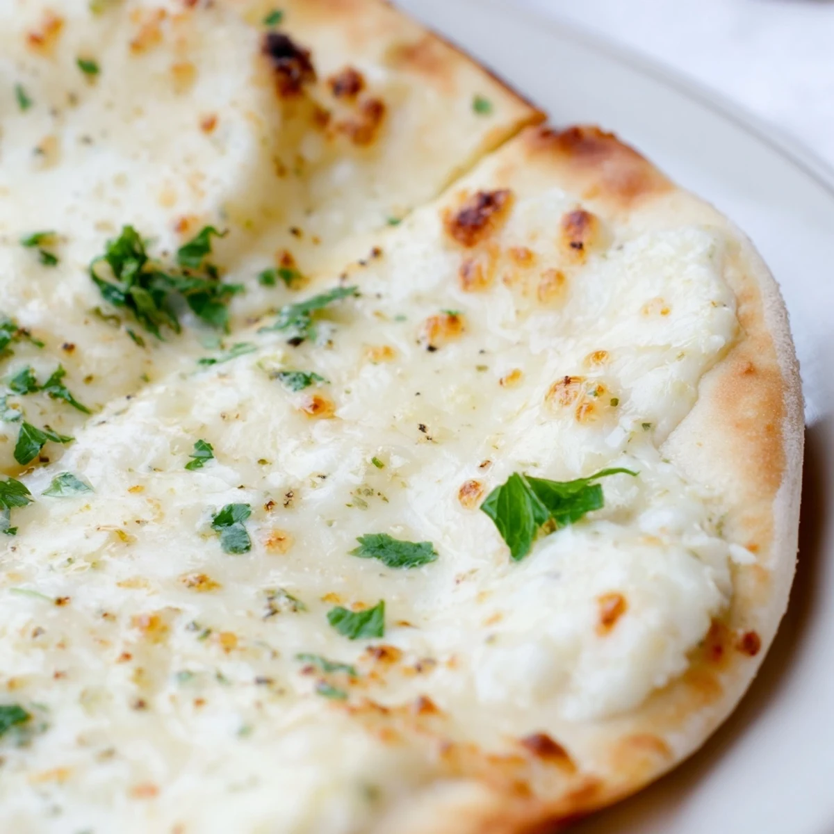 Golden-brown Creamy Garlic White pizza on a wooden board, garnished with fresh parsley and ready for dinner.
