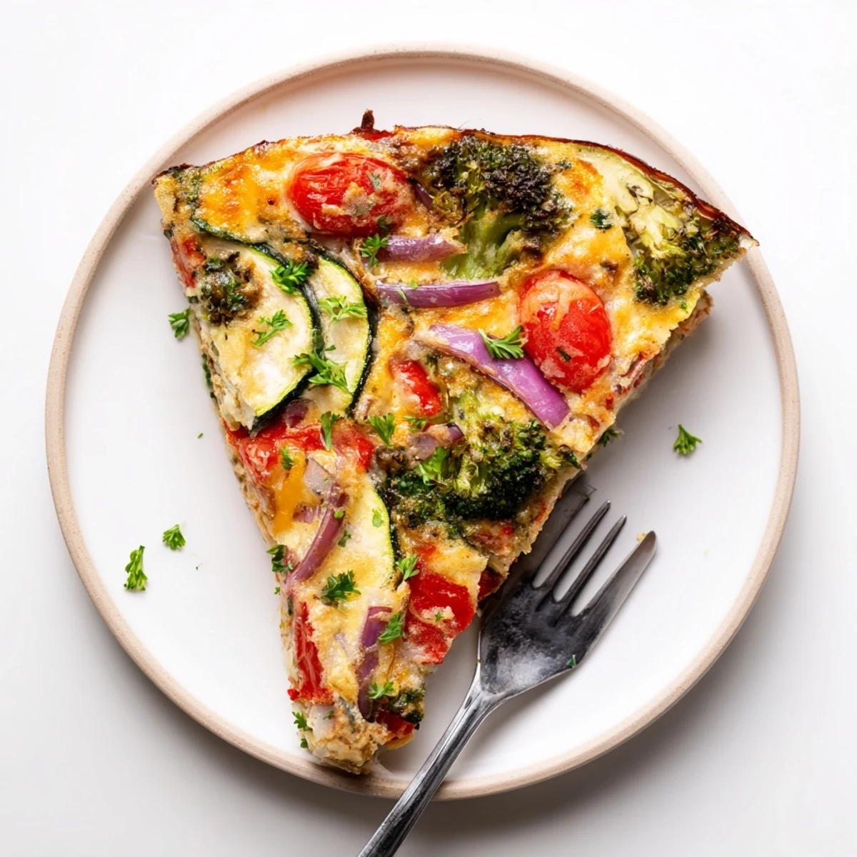 Golden-brown Vegetable Frittata baked in an oven-safe skillet, filled with broccoli, bell pepper, and cherry tomatoes.  