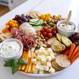 Delightful girl dinner platter filled with snacks, fresh veggies, and creamy cheeses.  