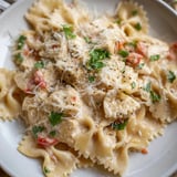 Delicious Mozzarella Garlic Butter Chicken Bowties atop al dente pasta, garnished beautifully.  