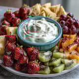 Vibrant spring fruit platter with strawberries, kiwi, and mango, served with creamy honey-yogurt dipping sauce for a refreshing snack.
