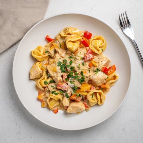 Zesty Cajun Garlic Parmesan Chicken Tortellini served with fresh parsley and creamy sauce.  