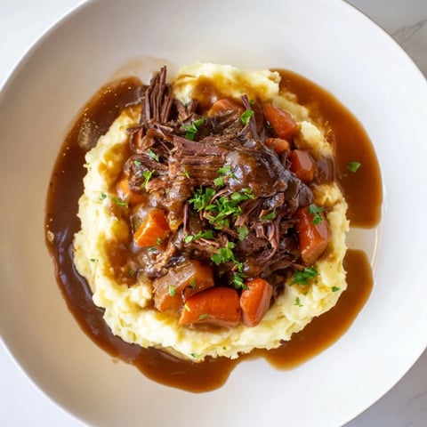 Tender Slow Cooker Pot Roast with vegetables and a generous serving of creamy mashed potatoes.