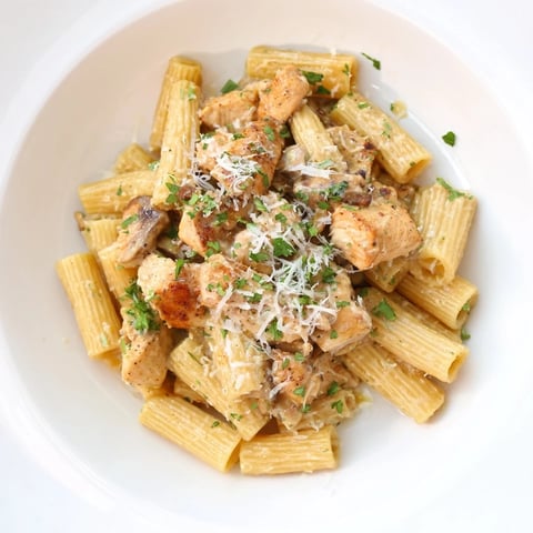 Steaming creamy garlic Parmesan chicken rigatoni, garnished with fresh parsley and extra cheese.