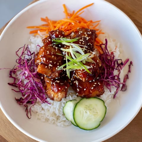 Sizzling Sriracha Honey Chicken Rice Bowl with a glistening sauce and colorful veggie toppings.