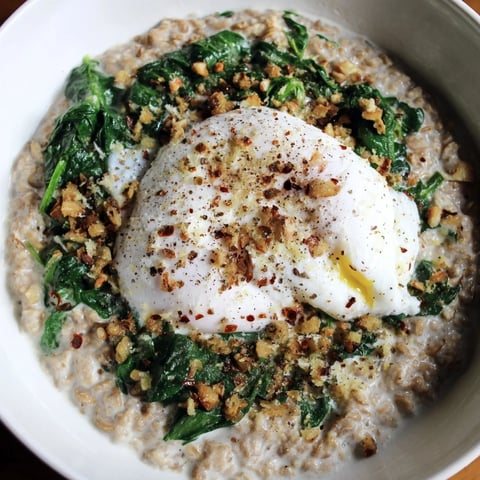 Warm bowl of savory oatmeal with spinach and poached egg, a comforting vegetarian breakfast.