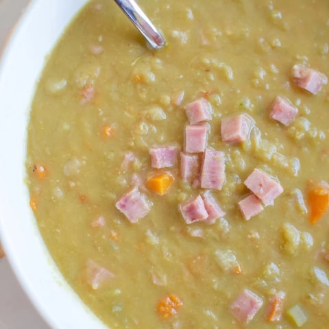 Steaming bowl of Hearty Split Pea and Ham Soup, with chunks of ham and vegetables, ready to serve.