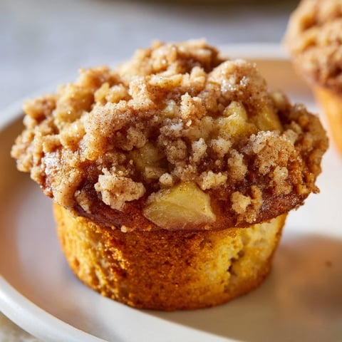 Golden-brown, crumb-topped tasty apple muffins bursting with cinnamon, perfect for breakfast.