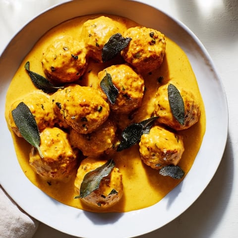 Golden-brown Easy Turkey Meatballs swimming in a creamy, vibrant pumpkin sage sauce, ready to serve.