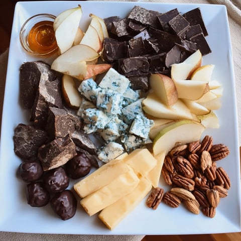 Rustic fireside comfort & cocoa platter overflowing with cheese, chocolate, and sliced fruit for sharing.
