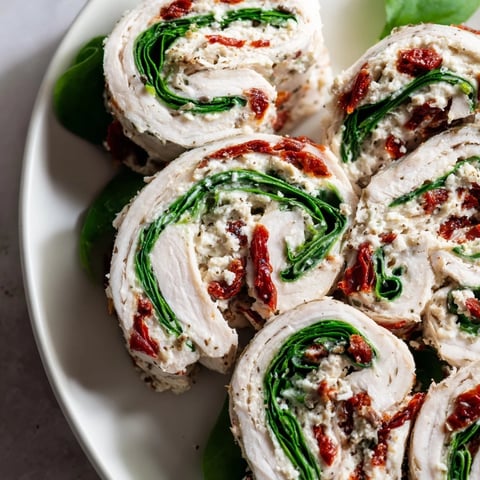 Vibrant photo of sun-dried tomato turkey roll-ups, showing layers of creamy filling and fresh spinach.