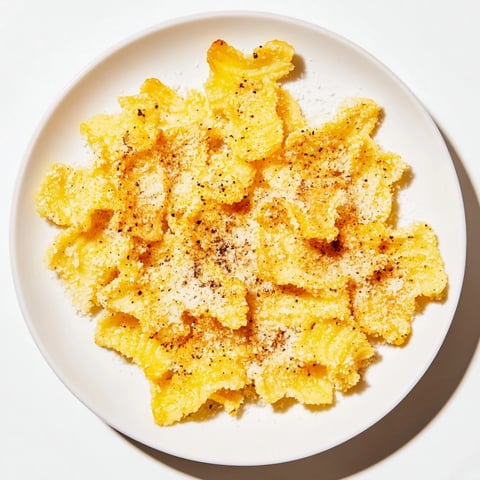 Golden, crispy pasta chips glistening from the air fryer, a savory snack idea you'll love.