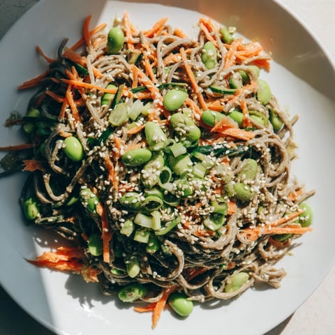 A colorful bowl overflows with Asian Sesame Noodle Salad, a refreshing vegetarian meal ready to eat.