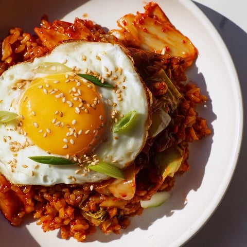 Steaming bowl of kimchi fried rice with a perfectly fried egg, ready to eat.