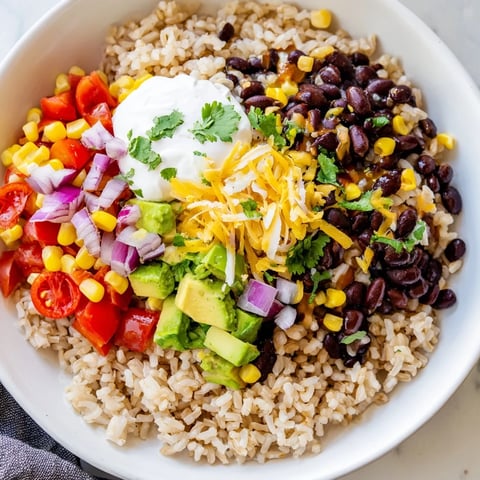 Golden brown rice burrito bowl layered with black beans and fresh vibrant vegetables in a vibrant image.