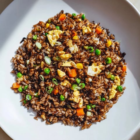 Steaming bowl of Black Garlic Fried Rice with vegetables, ready for a delicious Asian-inspired dinner.