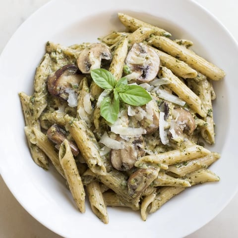 Creamy Mushroom Pesto Pasta served warm in a white bowl, garnished with fresh basil and a sprinkle of Parmesan cheese.  