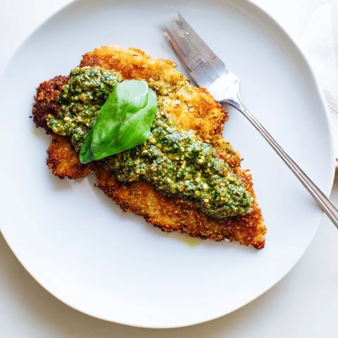 Golden-brown Crispy Pesto Chicken Cutlets served hot with a vibrant green basil dollop on top.  