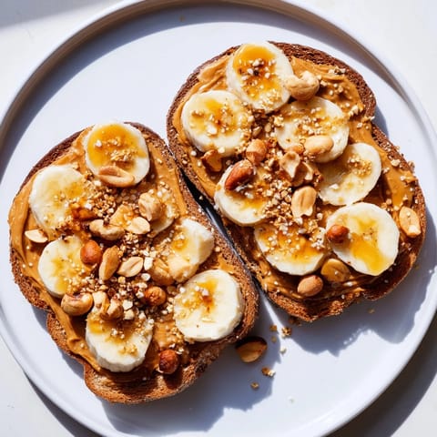 Crunchy peanut butter and banana sandwich with chopped peanuts and granola, a tasty snack.