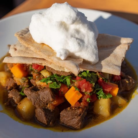A steaming bowl of Yemeni Saltah stew, a richly-spiced meat and vegetable medley with bread.