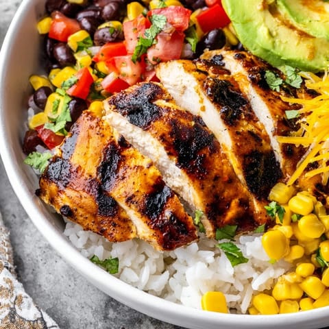A vibrant Spicy Chicken Burrito Bowl featuring charred chicken, fluffy rice, beans, and fresh cilantro garnish.  