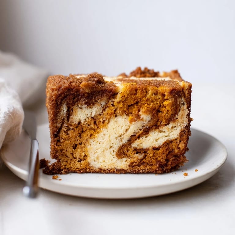 Swirled pumpkin cheesecake loaf with a warm, spiced churro topping ready to slice.  
