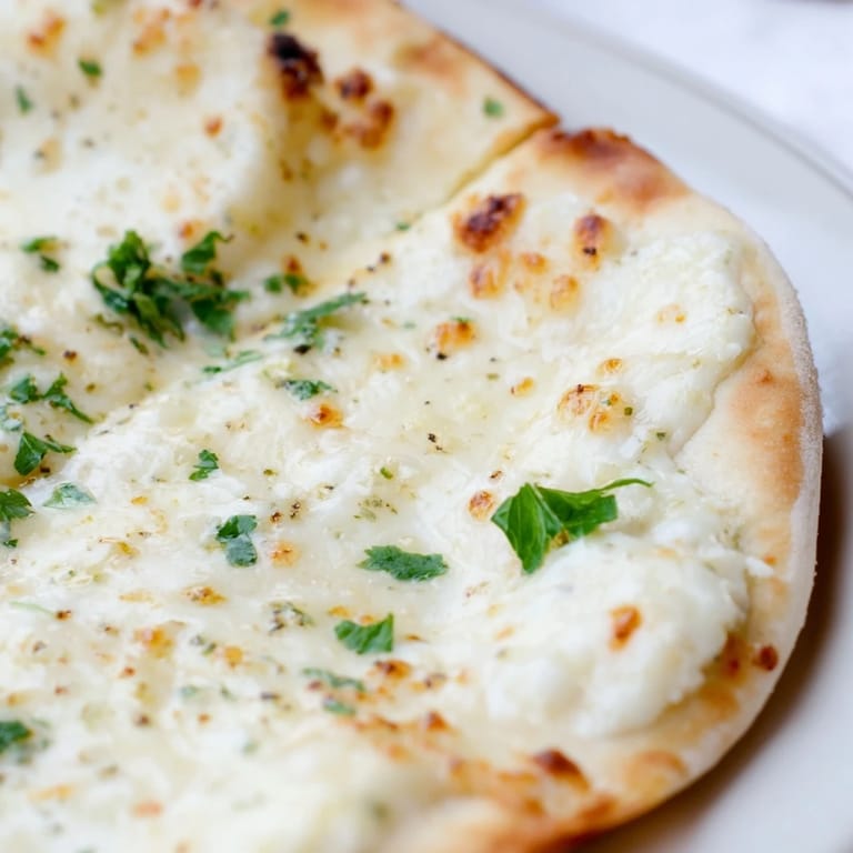 Golden-brown Creamy Garlic White pizza on a wooden board, garnished with fresh parsley and ready for dinner.