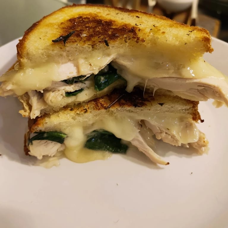 Close-up of a Grilled Chicken Spinach Panini with crispy edges, garlic butter, and vibrant green spinach.