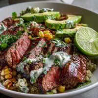 Juicy sliced steak, charred roasted corn, and creamy avocado fill this Tex-Mex bowl, topped with vibrant cilantro cream sauce.