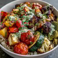 Rainbow Roasted Vegetable Bowl with vibrant, caramelized veggies over fluffy brown rice, finished with herb sauce.